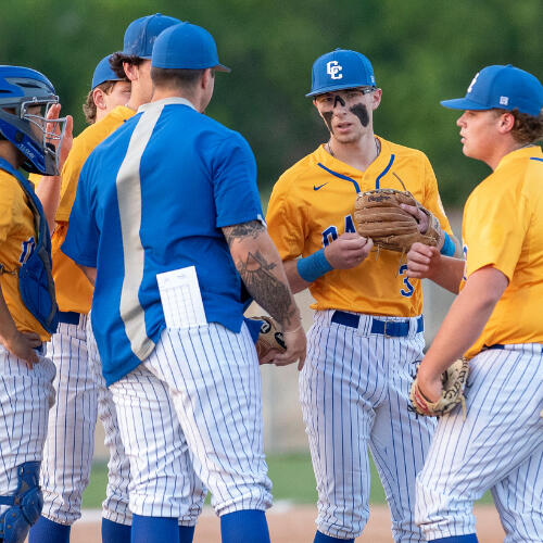 Baseball players talking to their coach on the field.